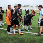 Pelatih mengajarkan teknik dasar sepak bola kepada pemain pemula